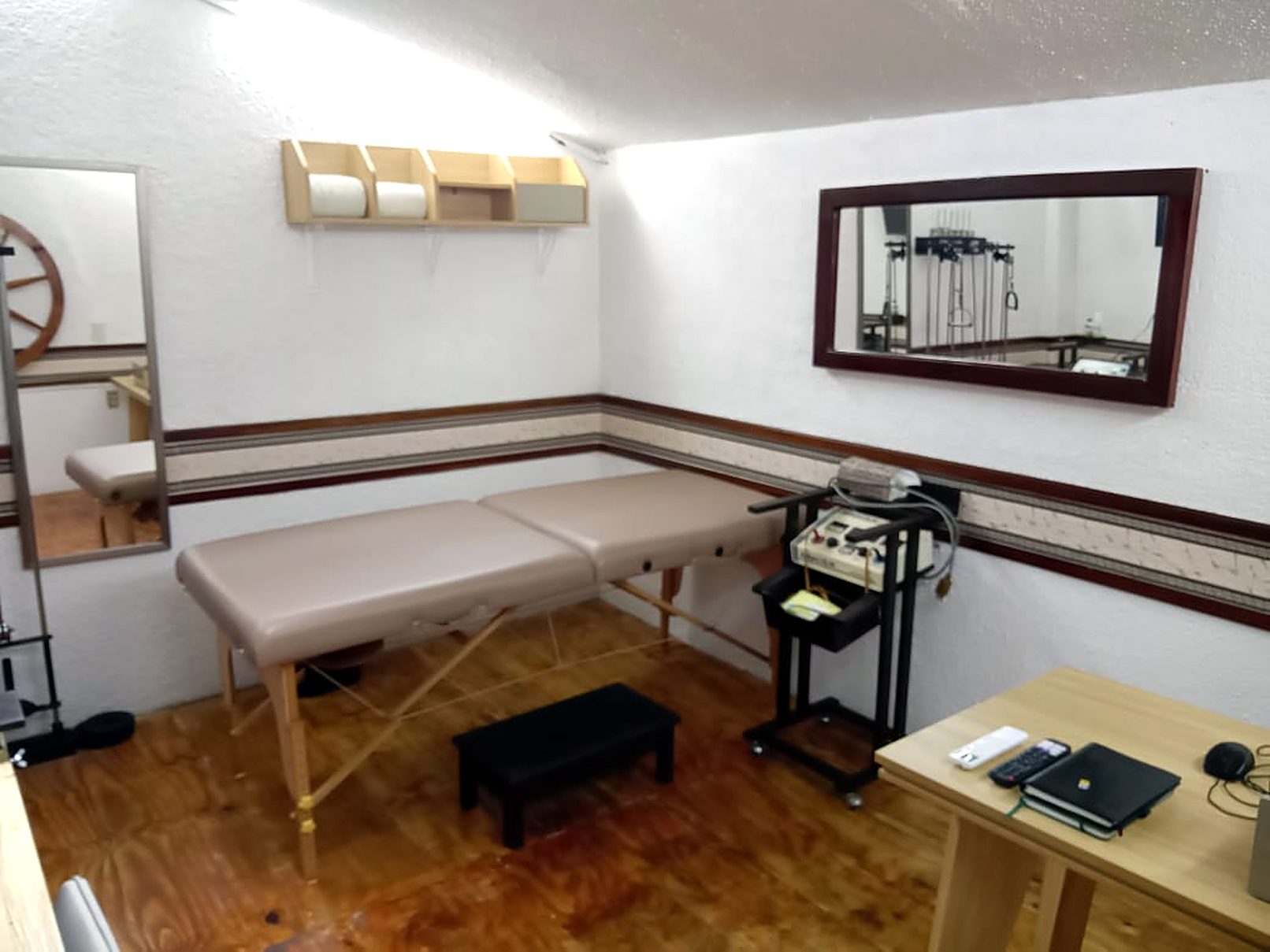 Cabina de terapia manual con camilla acolchada, equipo de electroterapia y espejo